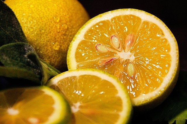 A picture of openly sliced bright yellow lemons, dripping with juice. There is a dark black background.  The purpose of this picture is to demonstrate how the mind can't tell the difference between reality and imagination. It's aim is to encourage optimism. 