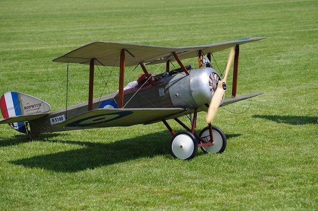 A picture on a green grass background of a world war 1 model biplane with blue, white and red livery . The aim of the picture is to encourage work life balance by doing a hobby.