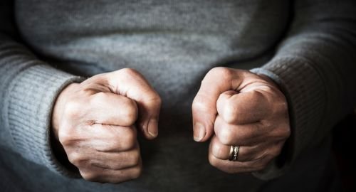 This is a picture of a possibly man wearing a grey jumper. Only the upper torso is visible and fills the whole of the picture. The man has two clenched fists indicating anger. The purpose of this picture is that Hypnotherapy Swindon can help with anger management.