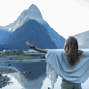 A blue picture with blue grey mountains in the background. There is a lake in front of the mountains and a woman in a blue shaw standing with outstretched arms. This picture represents freedom and is linked to EFT ( Emotional Freedom Technique ) and the freedom it can bring.
