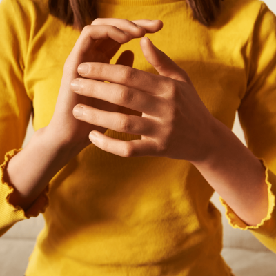 EFT Tapping A picture of a woman's torso wearing a yellow t-shirt. Only the arms and hands are visible. The hands are making a tapping gesture representing the Emotional Freedom Technique otherwise known as EFT